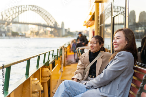 Leinwand Poster Happy Asian woman friends sitting on ferry boat crossing Sydney harbour in Australia