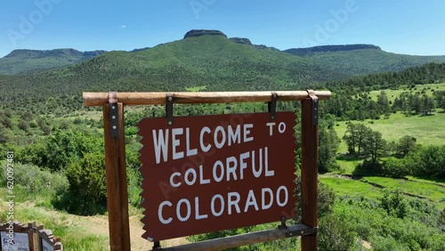 Welcome to Colorful Colorado sign along interstate highway with beautiful scenic lookout. Aerial rising shot revealing scenic mountains in CO. photo