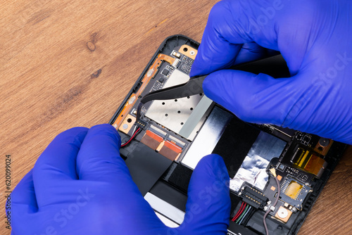 close-up of the work of a specialist in blue gloves on replacing an electronic board and disconnecting contacts for a new one, repair