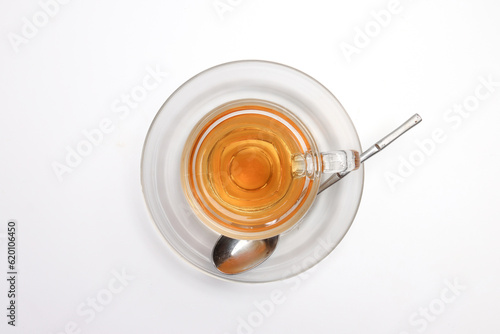 Hot tea in transparent glass cup saucer on white background