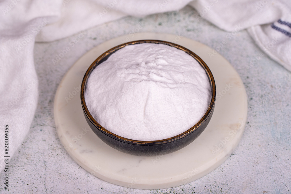 Sodium bicarbonate or baking soda on grey background. Sodium bicarbonate powder in bowl Sodium bicarbonate or baking soda on grey background. Sodium bicarbonate powder in bowl