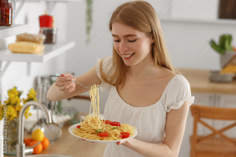 Young woman eating tasty pasta in kitchen Young woman eating tasty pasta in kitchen