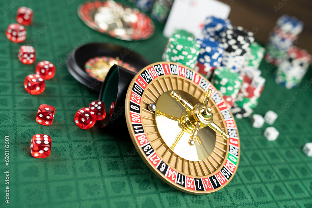 Casino. Gambling games theme. Roulette wheel, dice and poker chips on the casino felt green table. Casino. Gambling games theme. Roulette wheel, dice and poker chips on the casino felt green table.