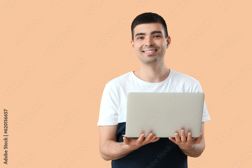 Young man with laptop on beige background Young man with laptop on beige background