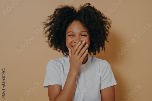 Tablou pe pânză Beautiful dark skinned millennial woman covering her mouth with hand while laugh