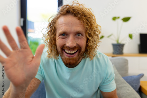 Happy caucasian man sitting on sofa and having video call