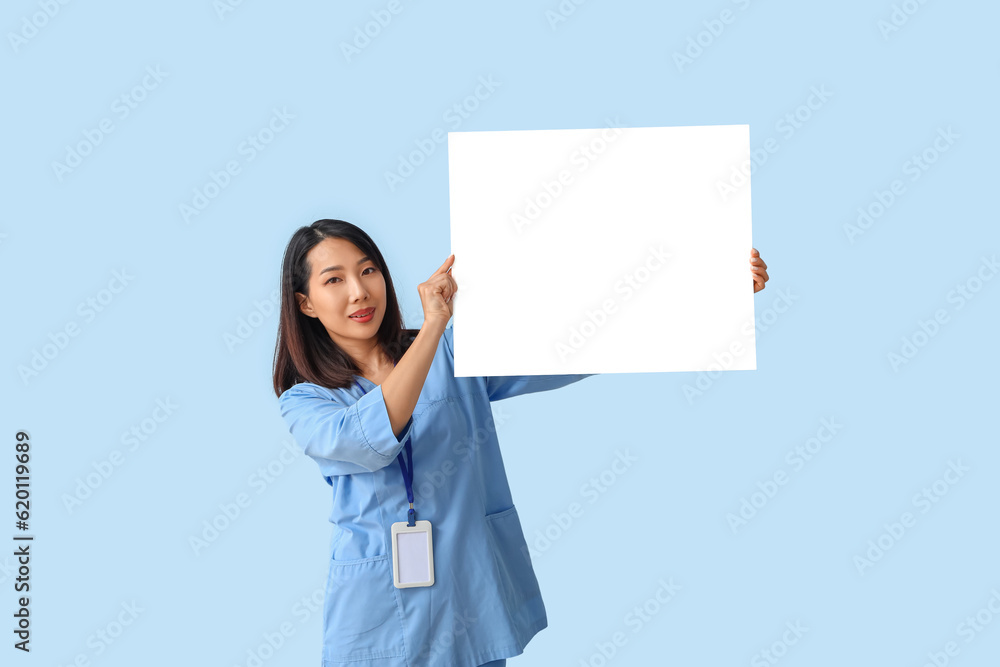 Female Asian medical intern with blank paper sheet on blue background Female Asian medical intern with blank paper sheet on blue background