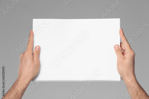 Wallpaper Mural Man holding sheet of paper on grey background, closeup. Mockup for design Torontodigital.ca