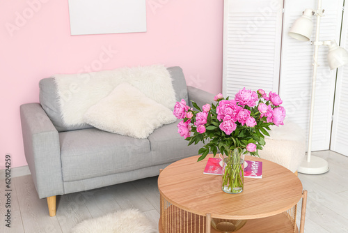Vase of pink peonies on coffee table with couch in living room © Pixel-Shot