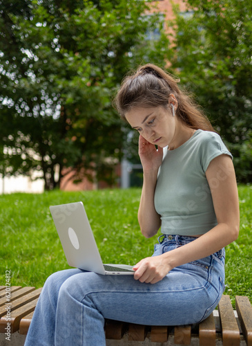 Young woman using laptop computer in park, freelance student girl working and studying online outdoors