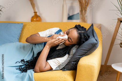 Woman blows her nose while resting at home due to illness.