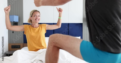 Joyful woman looks at man in shorts dancing in bedroom 4k movie. Intimate life in married couples concept photo