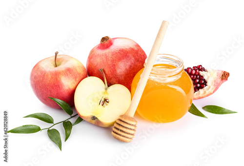 Jar of sweet honey, ripe pomegranate, apples and plant leaves on white background. Rosh hashanah (Jewish New Year) celebration photo