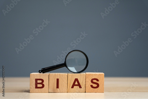 Bias word on a wooden blocks. Prejudice. Personal opinions. Preconception. Concept of facts and biases. Magnifying glass photo