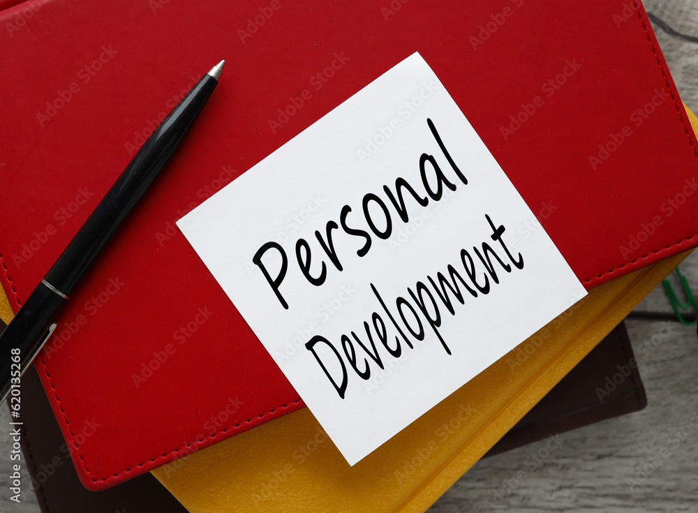 Personal development view from above. workspace with text on a white sticker on a red notepad. Personal development view from above. workspace with text on a white sticker on a red notepad.