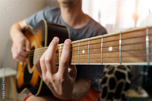 Man plays an acoustic guitar at home, close-up. Selective focus