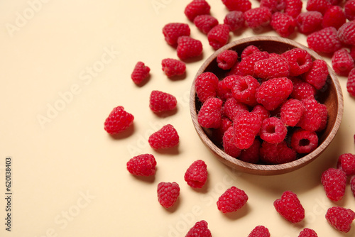 Bowl with fresh raspberries on yellow background