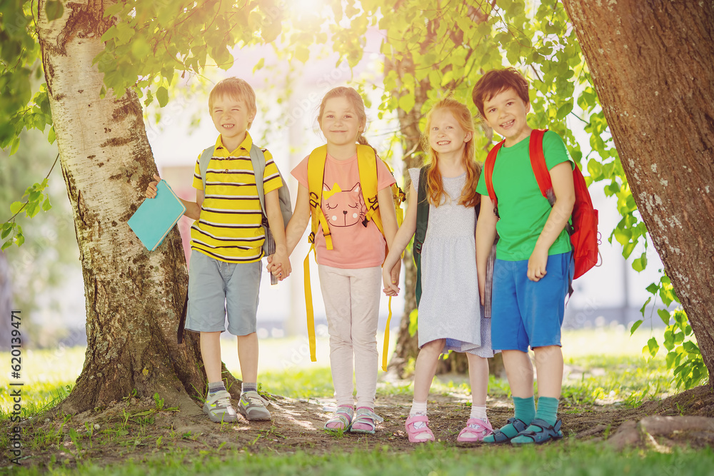 Fototapeta premium Group of children standing with backpacks near the school.