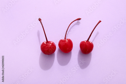 Tasty maraschino cherries on lilac background