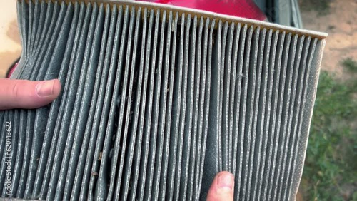 A dirty cabin filter just removed from the car in the hands of a man.