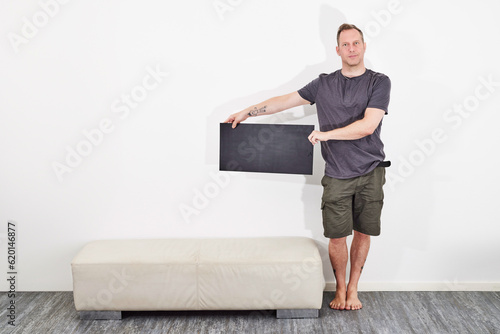 Man in shorts holding black sign barefoot