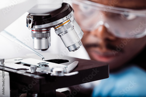 african american scientist in lab working with microscope