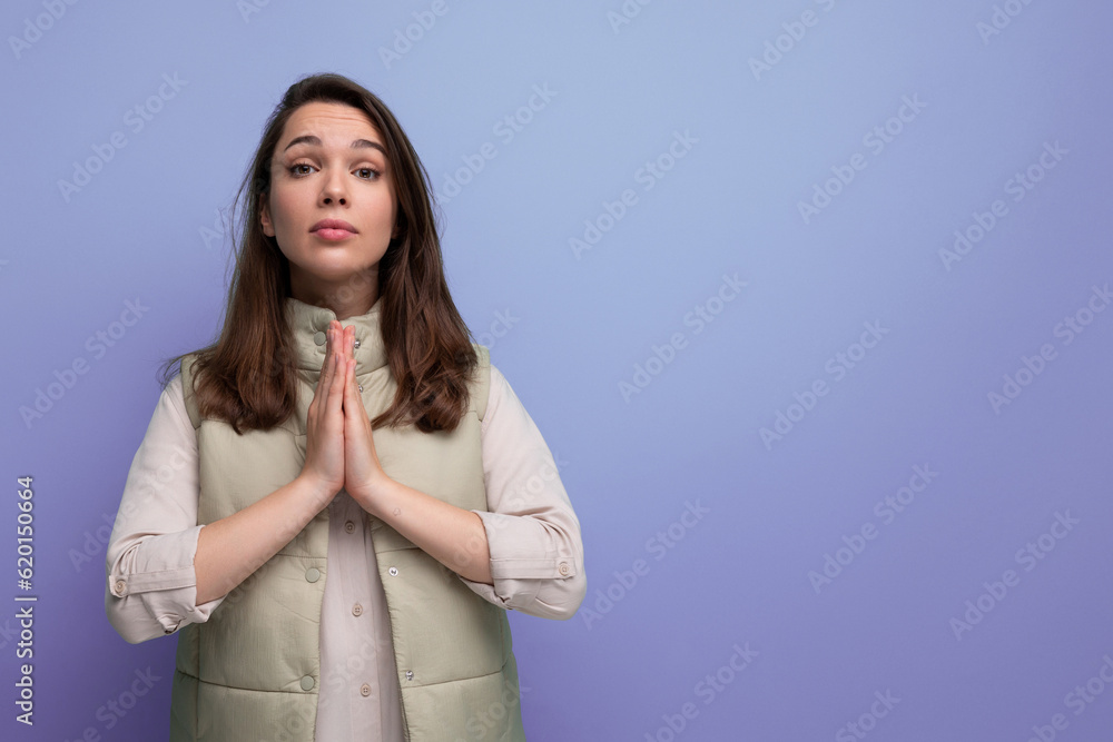 young brunette female adult in casual attire folded her hands for prayer and supplication young brunette female adult in casual attire folded her hands for prayer and supplication
