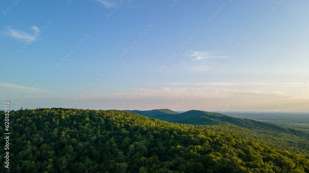 Aerial view of the Peak of the mountain range and tall forest near to the river at summer cloud evening with horizon, low height, blue Aerial view of the Peak of the mountain range and tall forest near to the river at summer cloud evening with horizon, low height, blue