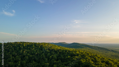 Aerial view of the Peak of the mountain range and tall forest near to the river at summer cloud evening with horizon  yellow color  low height
