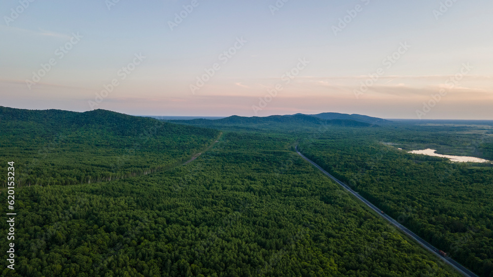 Aerial view of the Mountain range and tall forest near to the river at summer cloud evening with incredible horizon, orange color