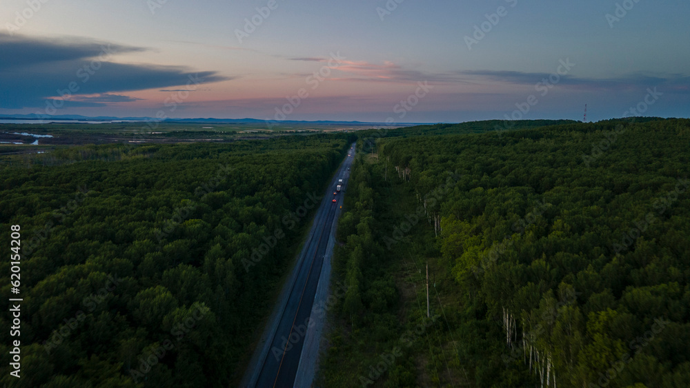 Aerial view of the Slope of a Mountain Range and tall taiga near to the river at summer cloud evening with horizon, purple