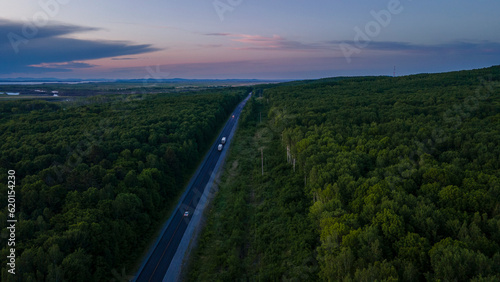 Aerial view of the Slope of a Mountain Range and tall taiga near to the river at summer cloud evening with horizon, purple color © Alex