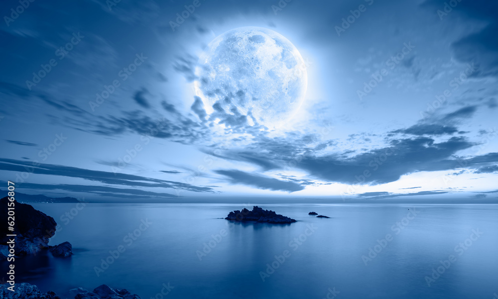 Night sky with blue moon in the clouds - Rocky coastline with power sea wave 
