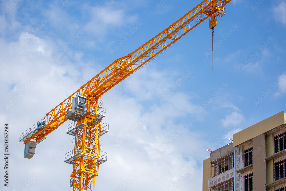 Load-lifting crane on a construction site against the blue sky. A group of lifting platforms for construction and handling operations. Close-up of a basket for transporting people Load-lifting crane on a construction site against the blue sky. A group of lifting platforms for construction and handling operations. Close-up of a basket for transporting people