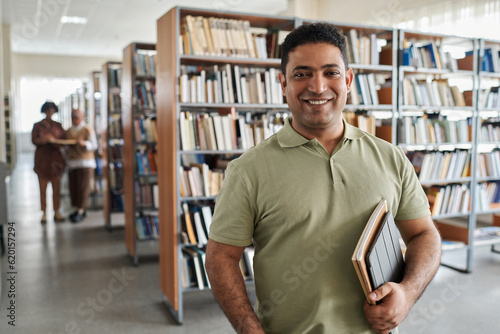 Portrait of adult student smiling at camera while standing in the library photo