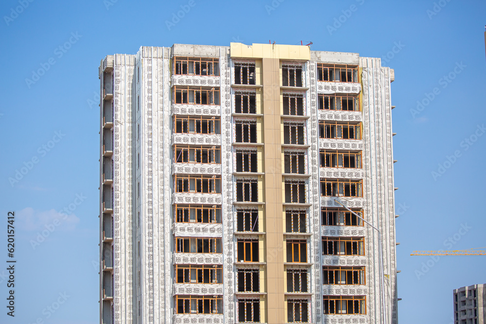 The construction team is working on the construction of the house. Artisans do their work in the open air. Scaffolding at the facade of the building. The construction team is working on the construction of the house. Artisans do their work in the open air. Scaffolding at the facade of the building.