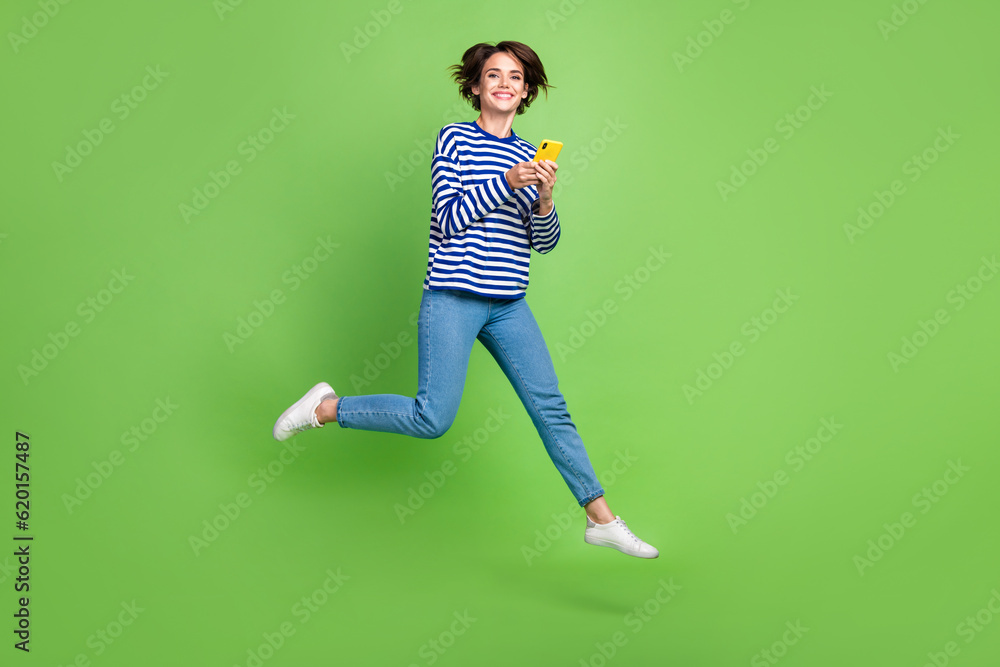 Full body photo of young funny woman running jumper with smartphone google gadget user ad samsung promo isolated on green color background