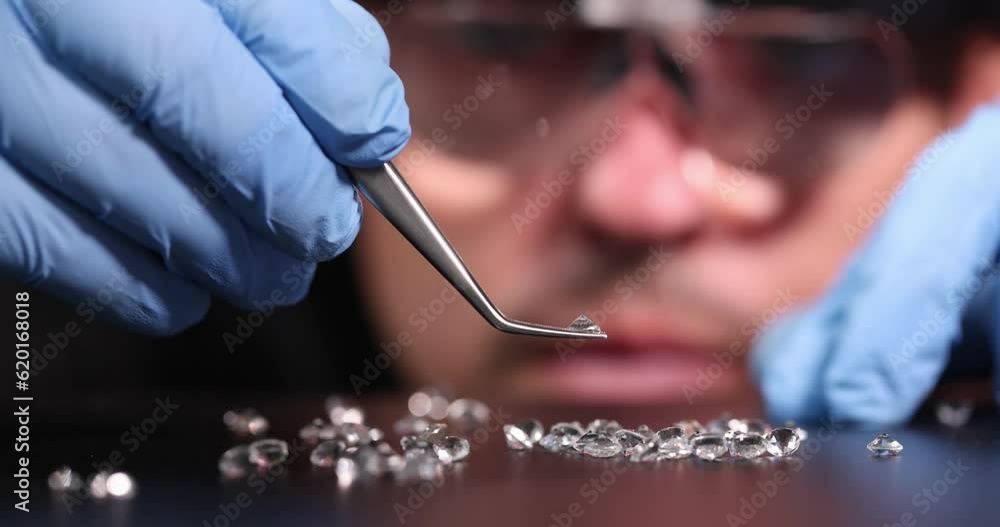 Jeweler with gloves and glasses checks authenticity of precious stones. Diamond making process concept Jeweler with gloves and glasses checks authenticity of precious stones. Diamond making process concept