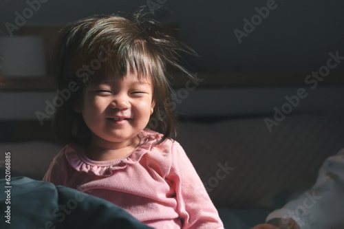 Asian baby girl wake up with frizzy hair at morning time , Girl have smiling, Happy family activity concept.