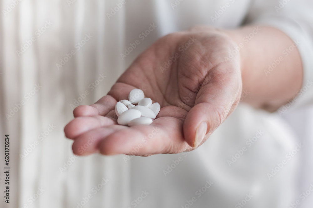 A handful of white pills in the hand of an elderly woman, close up.
A handful of white pills in the hand of an elderly woman, close up.