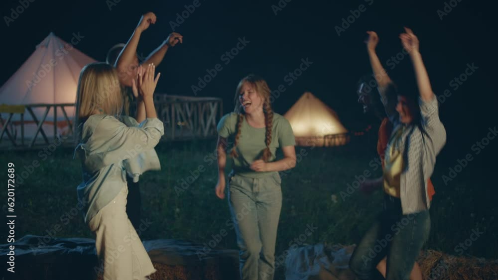 Excited ladies and guys have a party time in the middle of nature beside the fire stake they moving charismatic and smiling large enjoy the moment together at the campsite Excited ladies and guys have a party time in the middle of nature beside the fire stake they moving charismatic and smiling large enjoy the moment together at the campsite