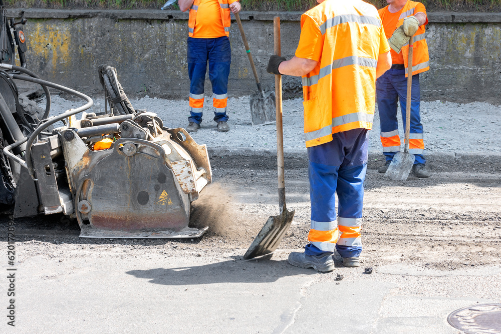 A road tractor with a powerful mounted mill removes a layer of old asphalt on the roadway. A road tractor with a powerful mounted mill removes a layer of old asphalt on the roadway.