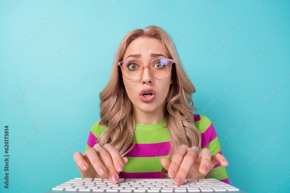 Portrait of astonished worried nervous girl with wavy hairdo wear stylish clothes staring at monitor isolated on blue color background Portrait of astonished worried nervous girl with wavy hairdo wear stylish clothes staring at monitor isolated on blue color background