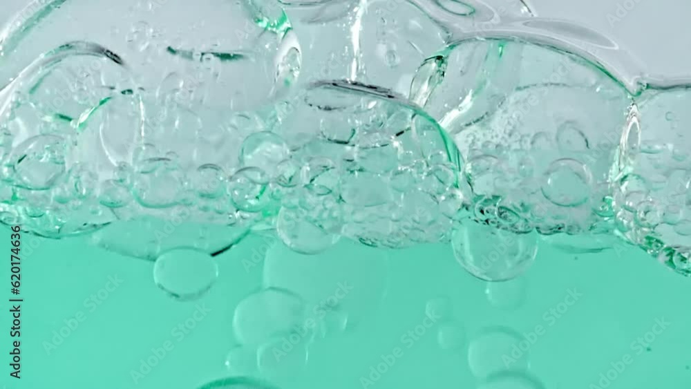 Slow Motion of Moving Oil, Air Bubbles in Water Rising up on Light White Background. Transparent cosmetic gel fluid with bubbles. Macro Shot. Closeup. Slow Motion of Moving Oil, Air Bubbles in Water Rising up on Light White Background. Transparent cosmetic gel fluid with bubbles. Macro Shot. Closeup.