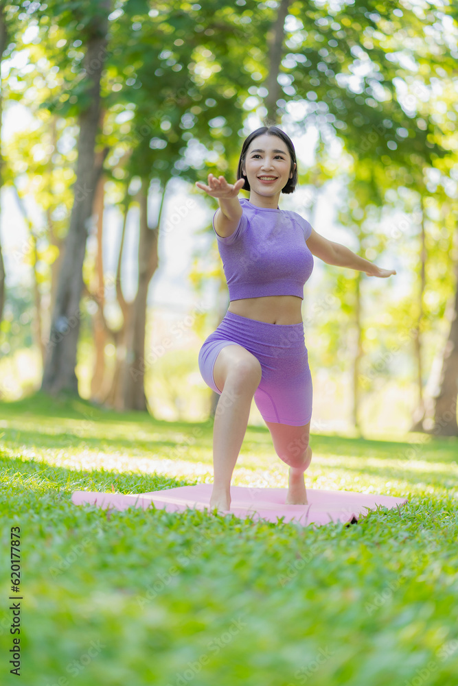 Healthy Thai Asian woman doing yoga in the evening at the park. Health and outdoor activities concept with plants as background on green grass. vertical image Healthy Thai Asian woman doing yoga in the evening at the park. Health and outdoor activities concept with plants as background on green grass. vertical image
