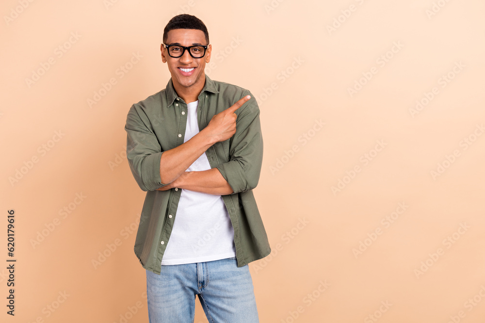 Photo of cheerful confident person toothy smile indicate finger empty space offer news isolated on beige color background Photo of cheerful confident person toothy smile indicate finger empty space offer news isolated on beige color background