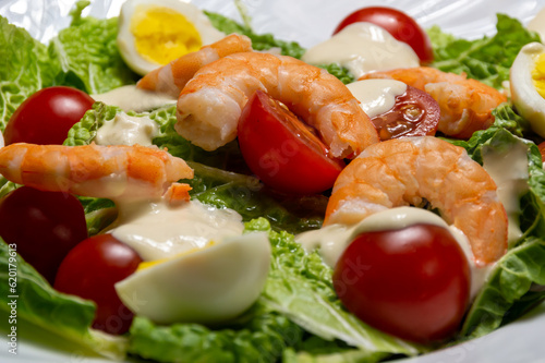Salad with shrimp tails, tomatoes, quail eggs and white sauce