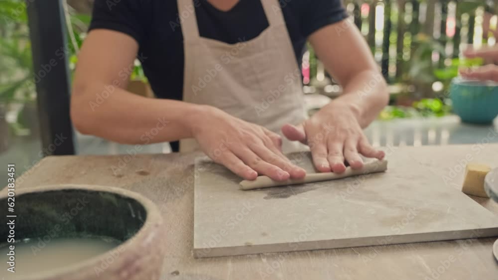 Man and woman in process of sculpting clay figure and making it wet on desk in workshop Man and woman in process of sculpting clay figure and making it wet on desk in workshop