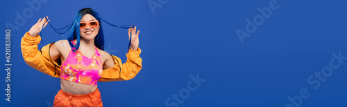 Fotografie fashion statement, positive female model with blue hair and trendy sunglasses is