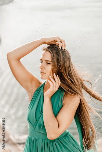 Woman sea green dress. Portrait of a happy woman with long hair in a long mint dress posing on a beach with calm sea bokeh lights on sunny day. Girl on the nature on blue sky background.